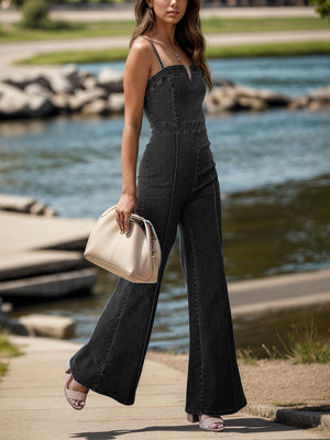 a woman in a black jumpsuit is holding a handbag