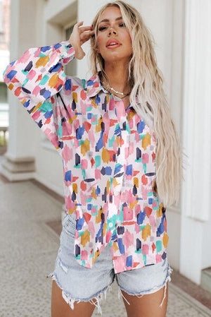 a woman wearing a colorful shirt and denim shorts