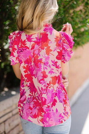 a woman wearing a pink floral top and jeans