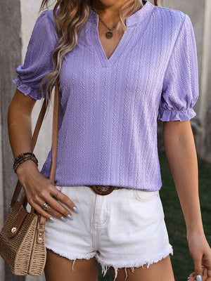 a woman wearing a purple top and white shorts