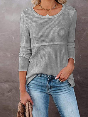 a woman wearing a gray sweater and jeans