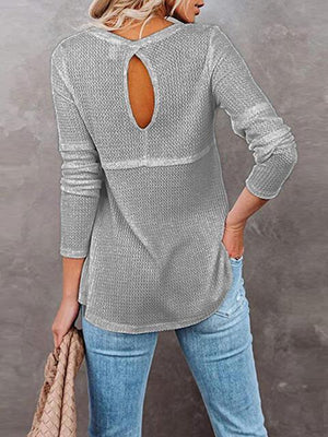 a woman wearing a grey sweater with a cut out back