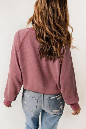 a woman wearing a pink sweater and ripped jeans