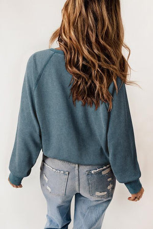 a woman wearing a blue sweater and ripped jeans