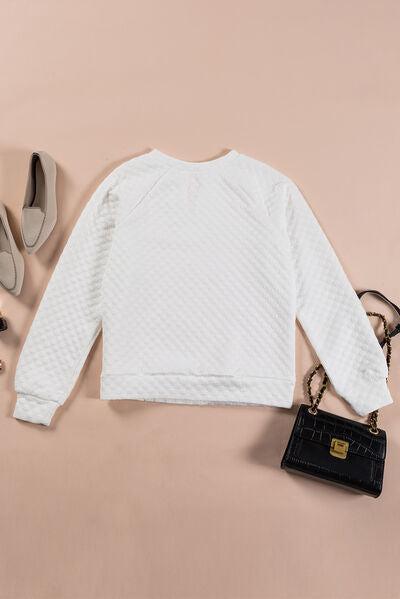 a white sweater, black purse, and shoes on a pink background