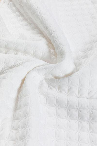 a close up of a white quilt on a bed