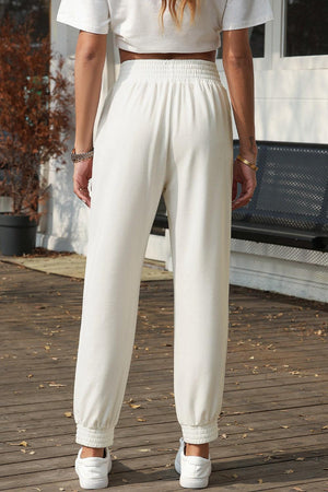 a woman standing on a deck wearing white pants