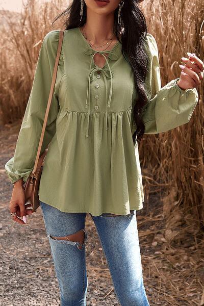 a woman wearing a green blouse and ripped jeans