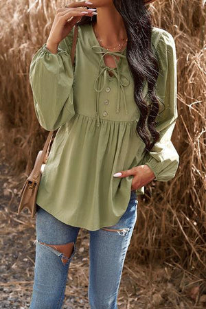 a woman wearing a green blouse and ripped jeans