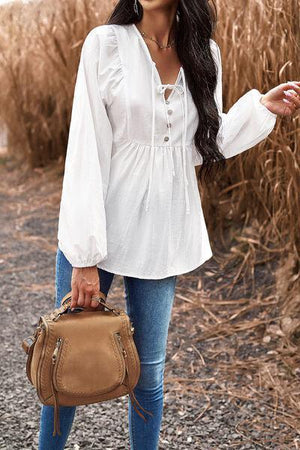 a woman in a white shirt and jeans holding a brown purse