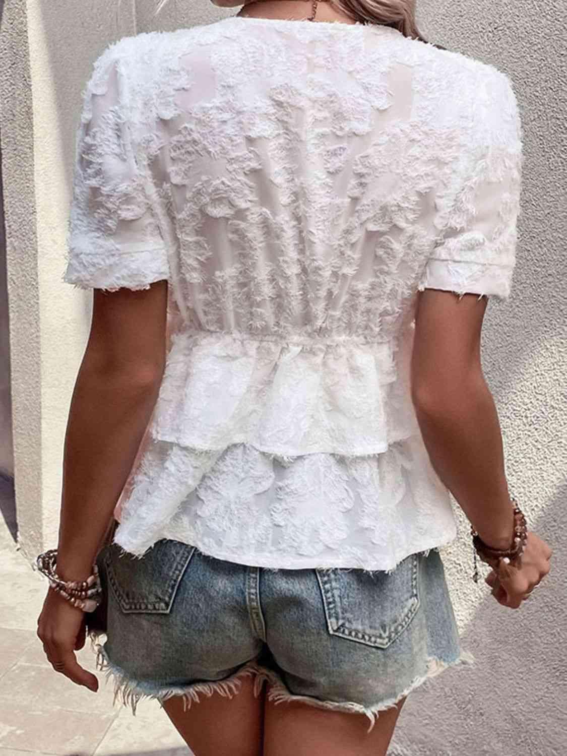 a woman wearing a white top and denim shorts