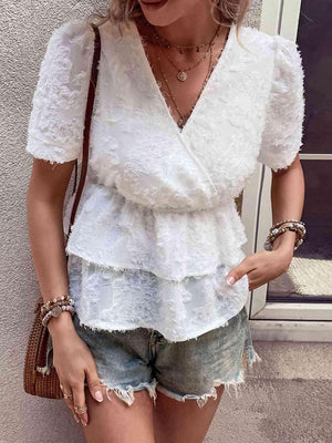 a woman wearing a white top and denim shorts