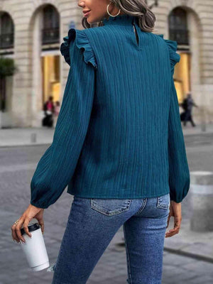 a woman wearing a green blouse and jeans