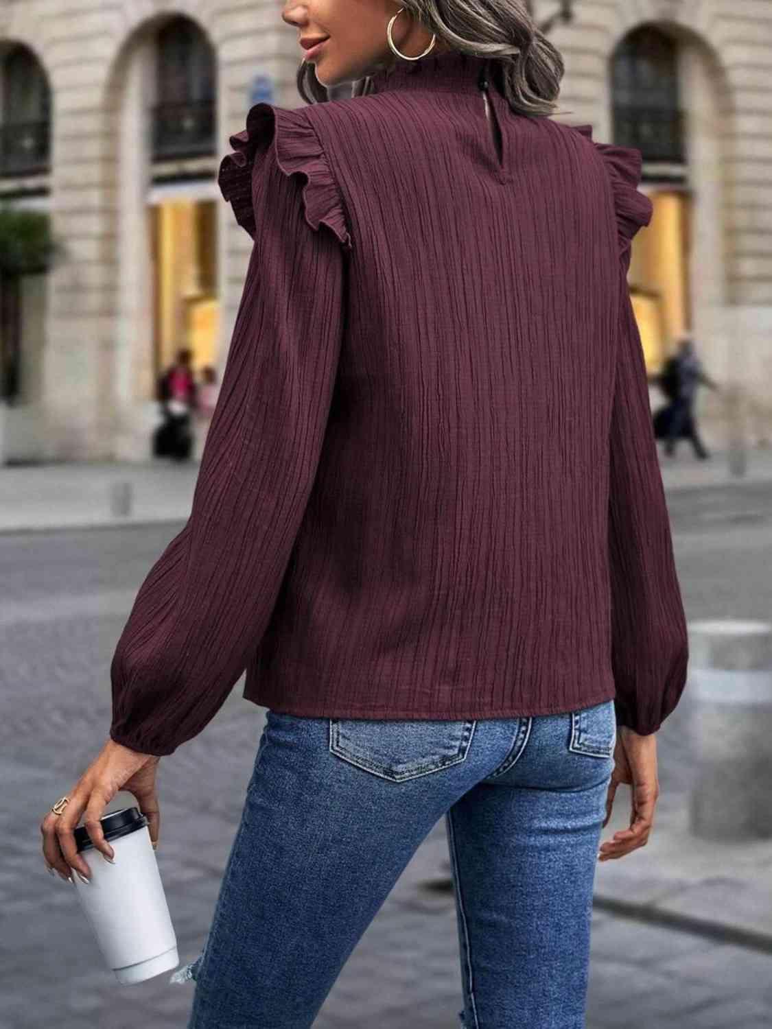 a woman wearing a maroon top and jeans