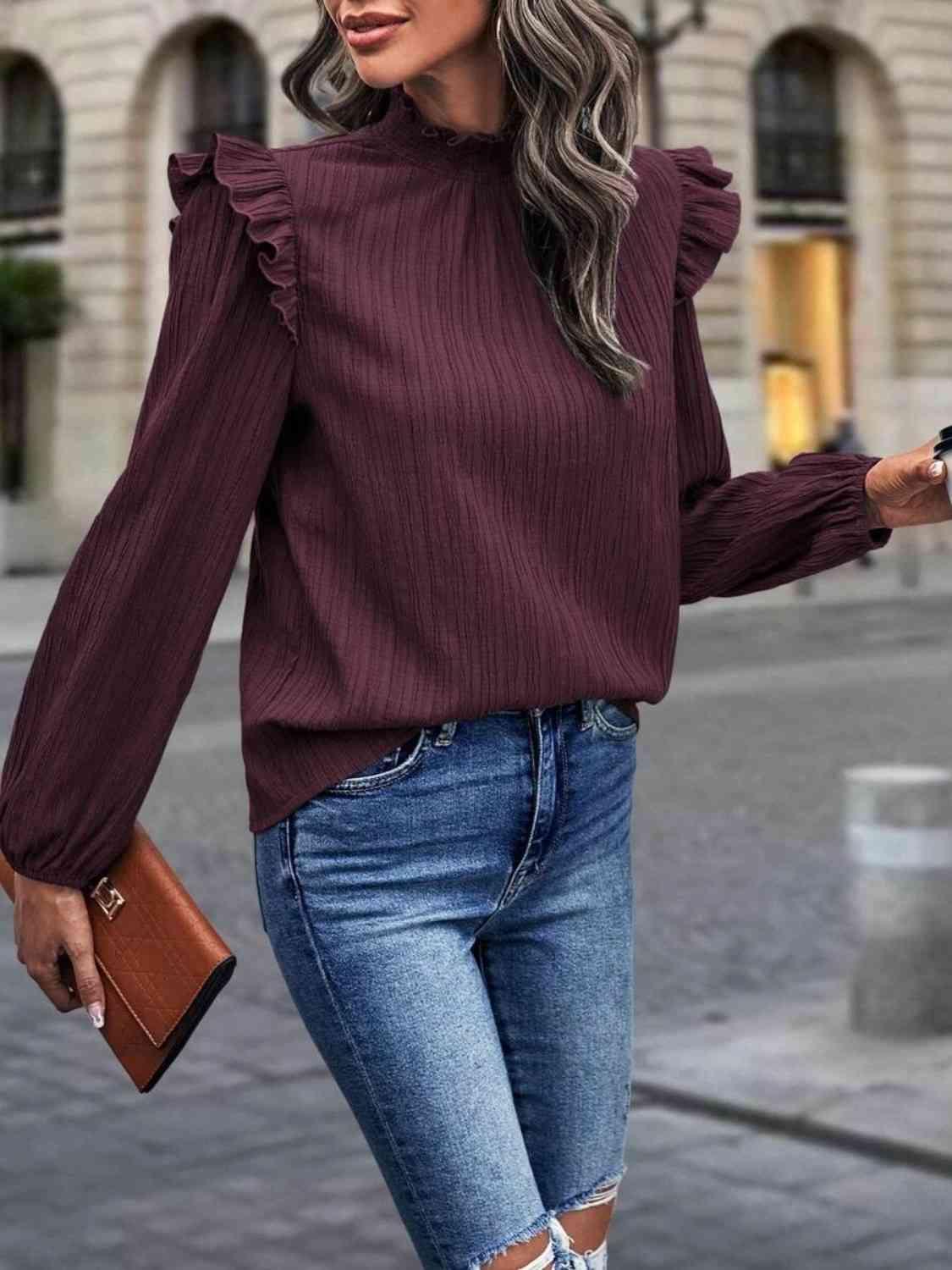 a woman wearing a burgundy top and ripped jeans