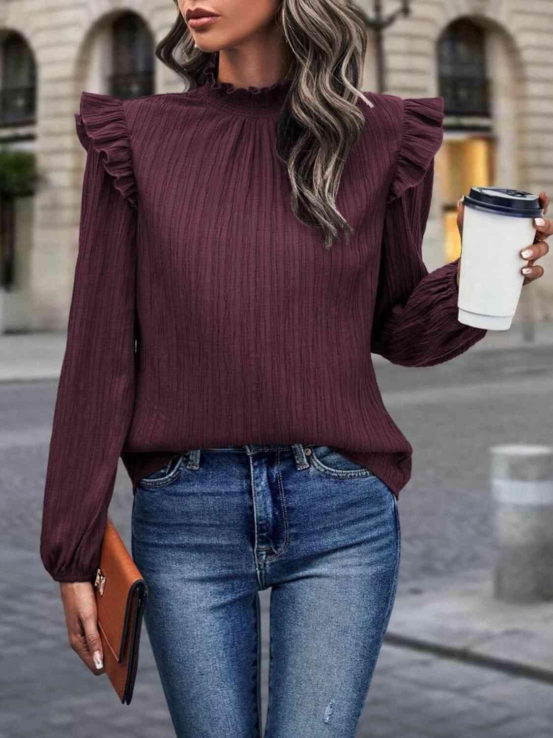 a woman in a burgundy top holding a cup of coffee