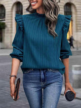 a woman wearing a green blouse and jeans