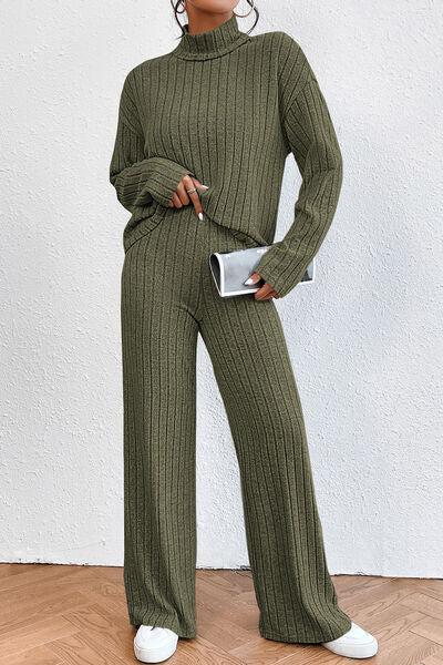 a woman in a green sweater and wide legged pants