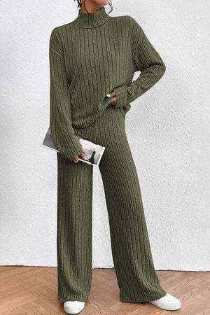 a woman in a green sweater and wide legged pants