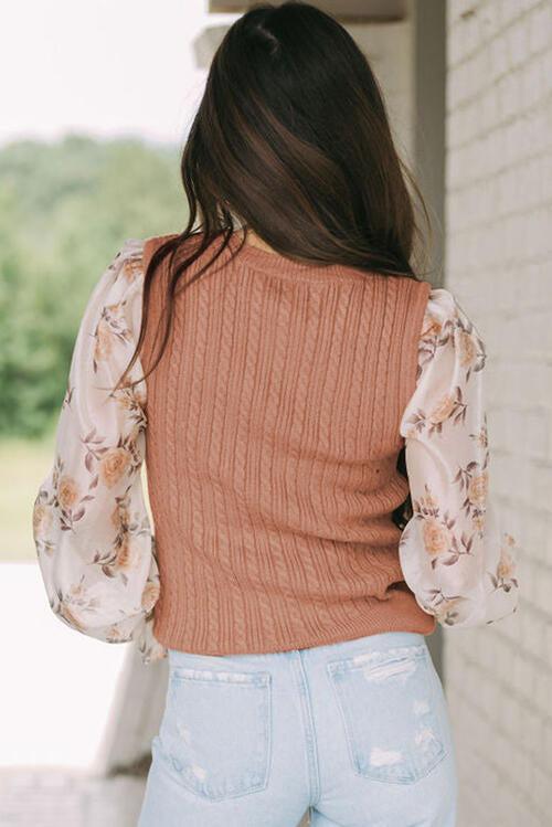 a woman wearing a sweater and jeans standing in front of a brick wall