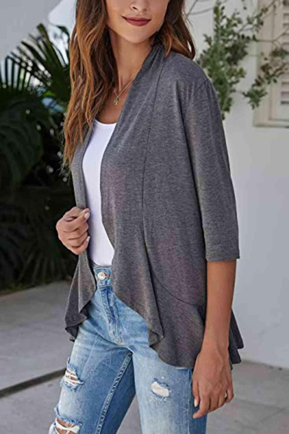 a woman wearing ripped jeans and a gray cardigan