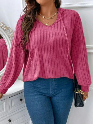 a woman standing in front of a mirror wearing a pink sweater