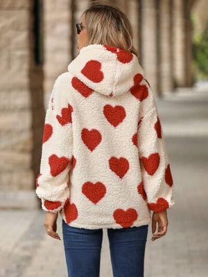 a woman wearing a red and white sweater with hearts on it