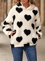 a woman in a white sweater with black hearts on it