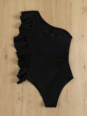 a black one piece swimsuit laying on a wooden floor