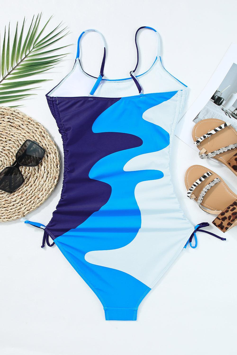 a blue and white one piece swimsuit next to a straw hat
