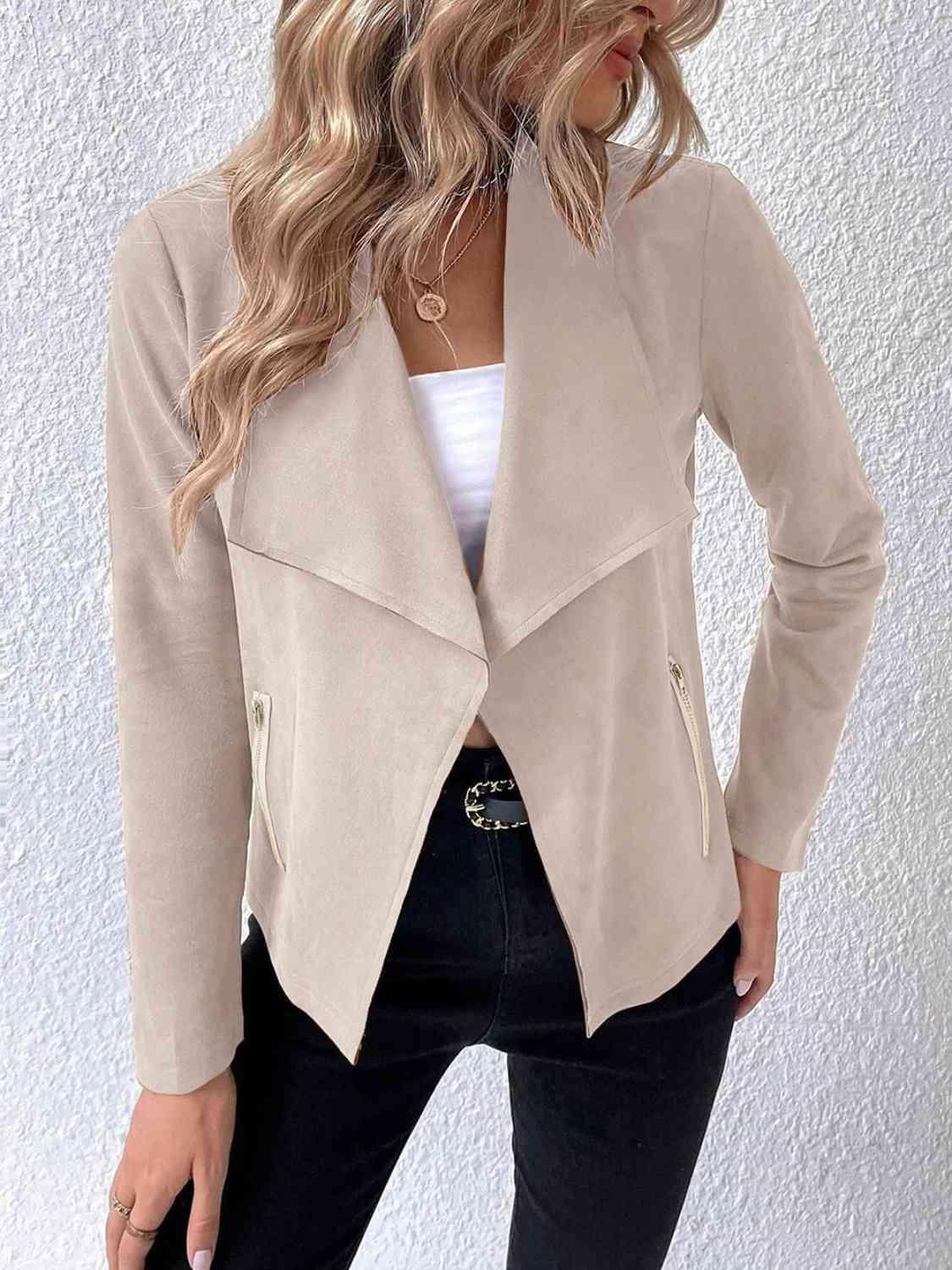 a woman wearing a beige jacket and jeans