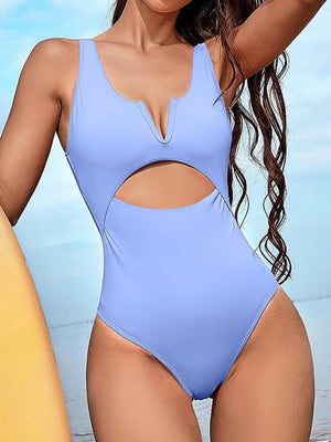 a woman in a blue one piece swimsuit holding a surfboard
