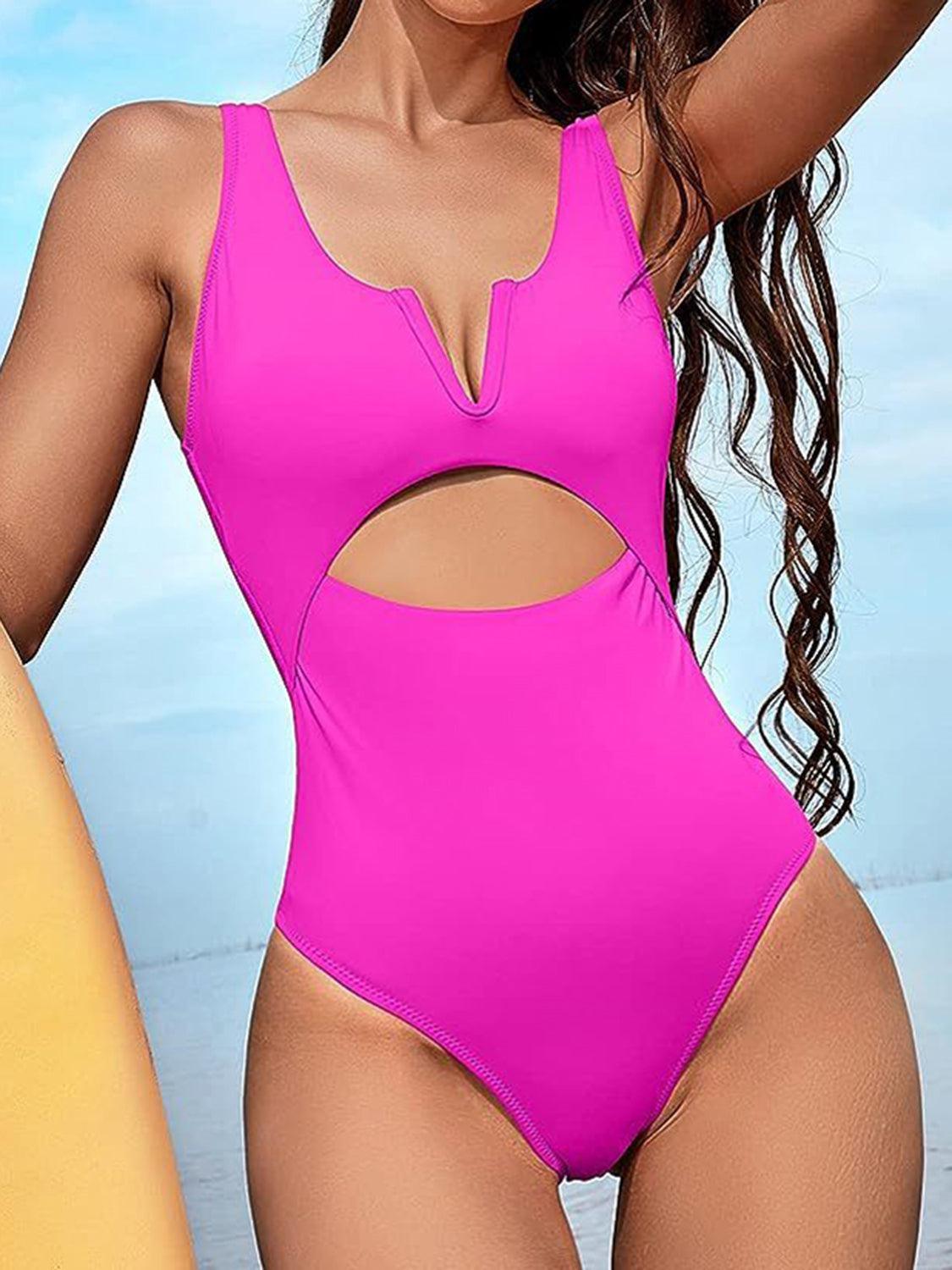 a woman in a pink one piece swimsuit holding a surfboard