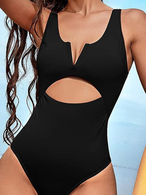 a woman in a black one piece swimsuit holding a surfboard