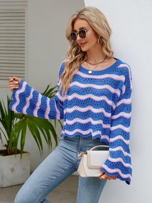 a woman leaning against a wall wearing a blue and white striped sweater