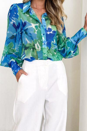 a woman wearing a blue and green shirt and white pants