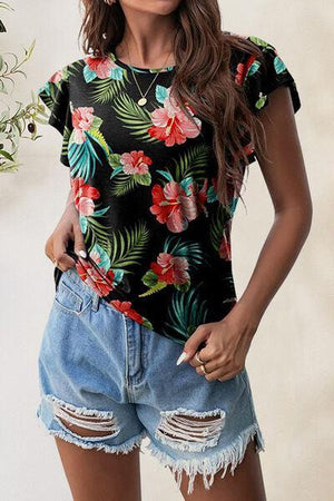 a woman wearing a floral top and ripped shorts