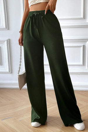 a woman wearing a crop top and green pants