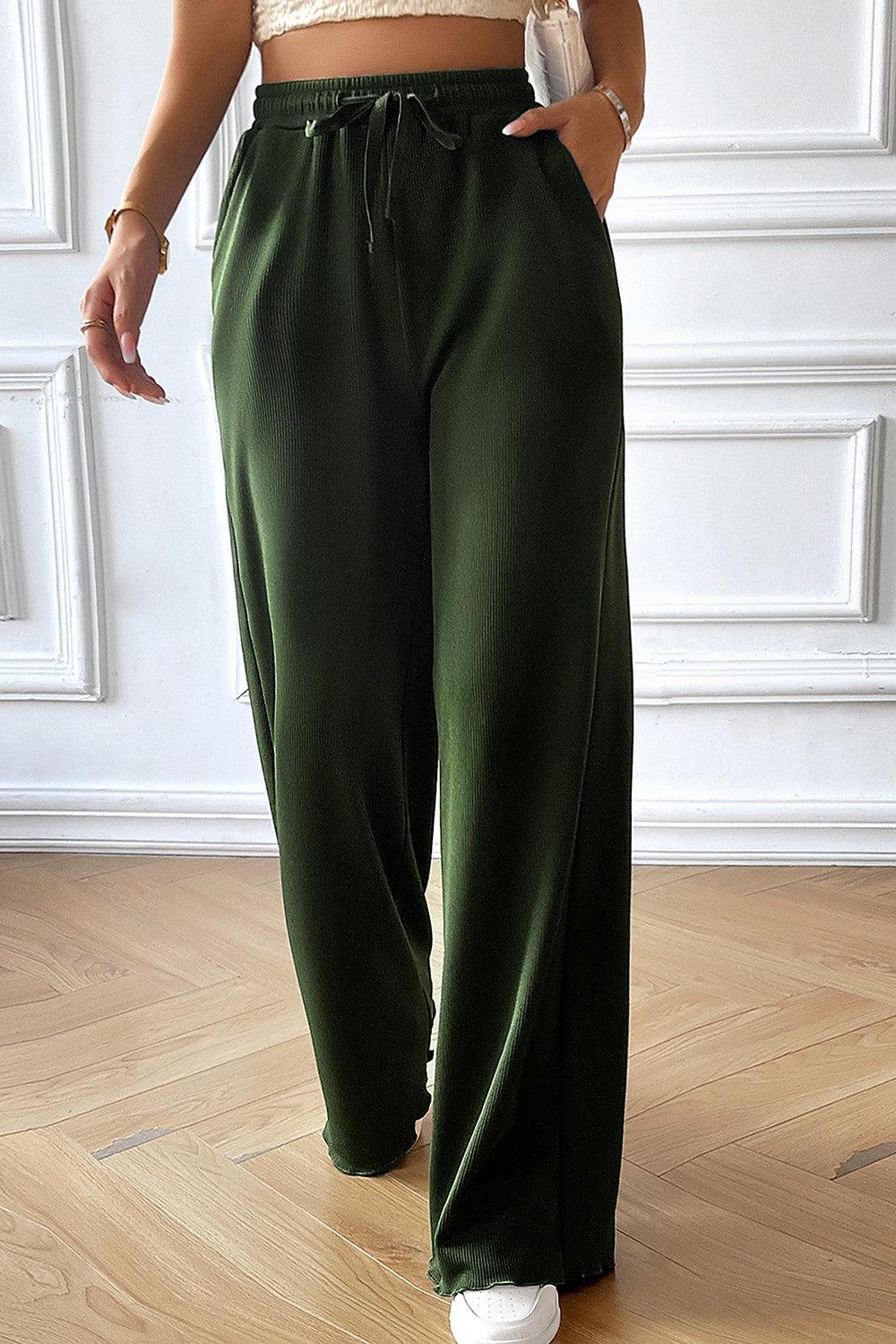 a woman in a crop top and green pants