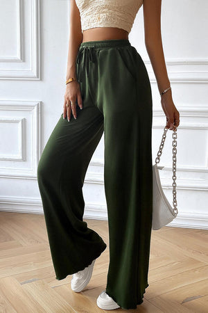 a woman in a crop top and green pants