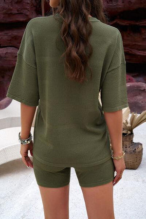 a woman wearing a green sweater and shorts