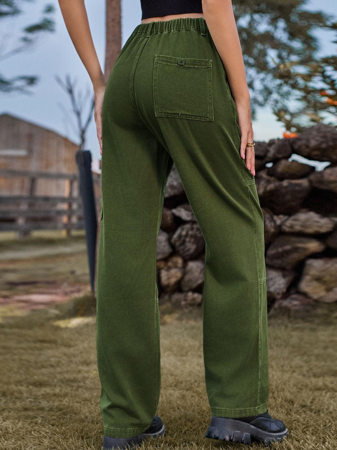 a woman in a black top and green pants