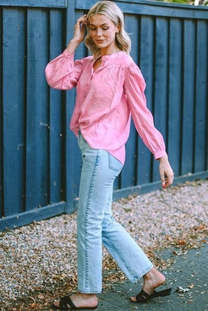 a woman in a pink shirt and jeans talking on a cell phone