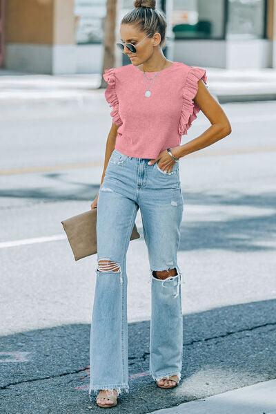 a woman wearing a pink top and ripped jeans