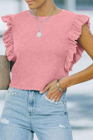 a woman wearing a pink top and ripped jeans