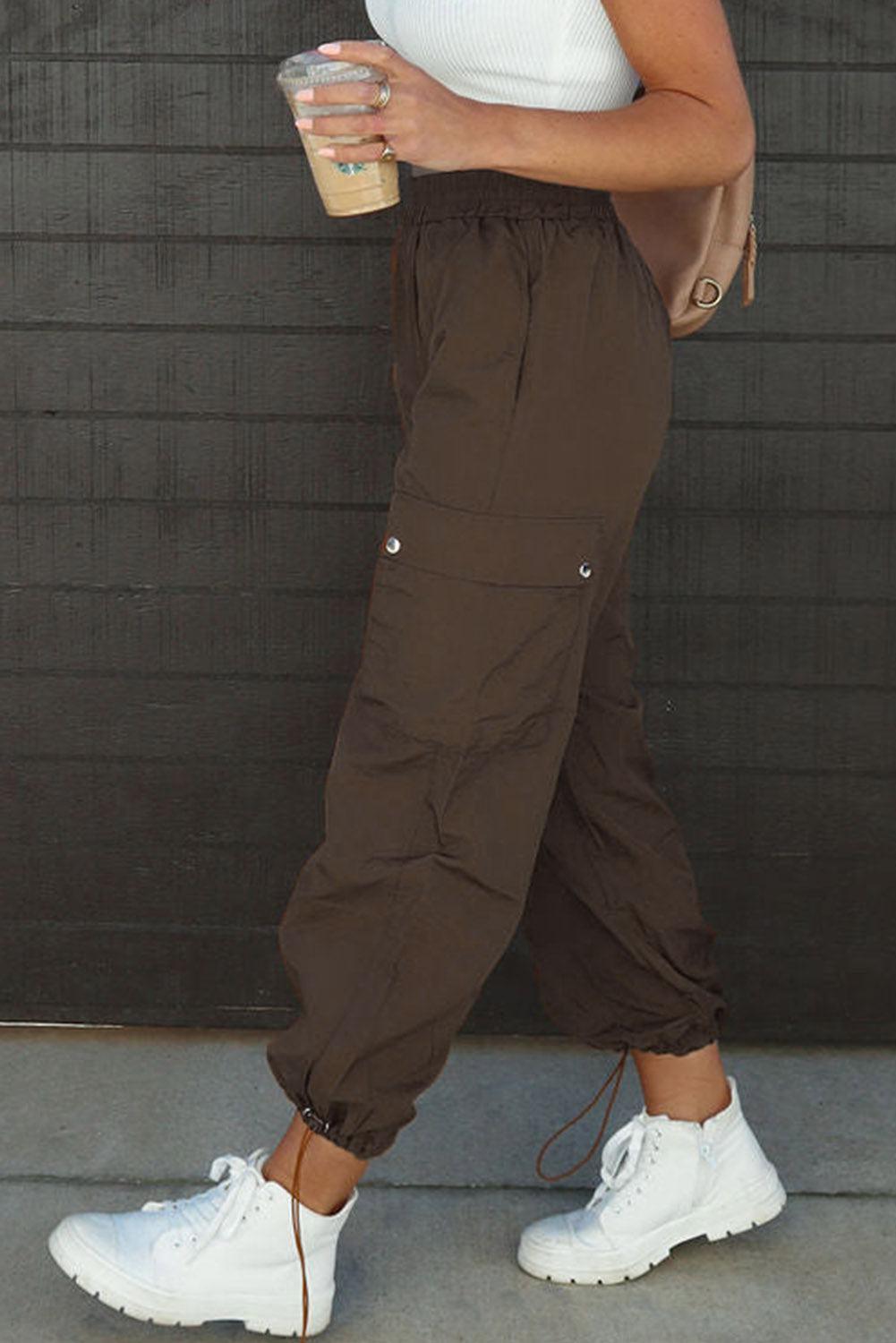 a woman in white shirt and brown pants holding a cup