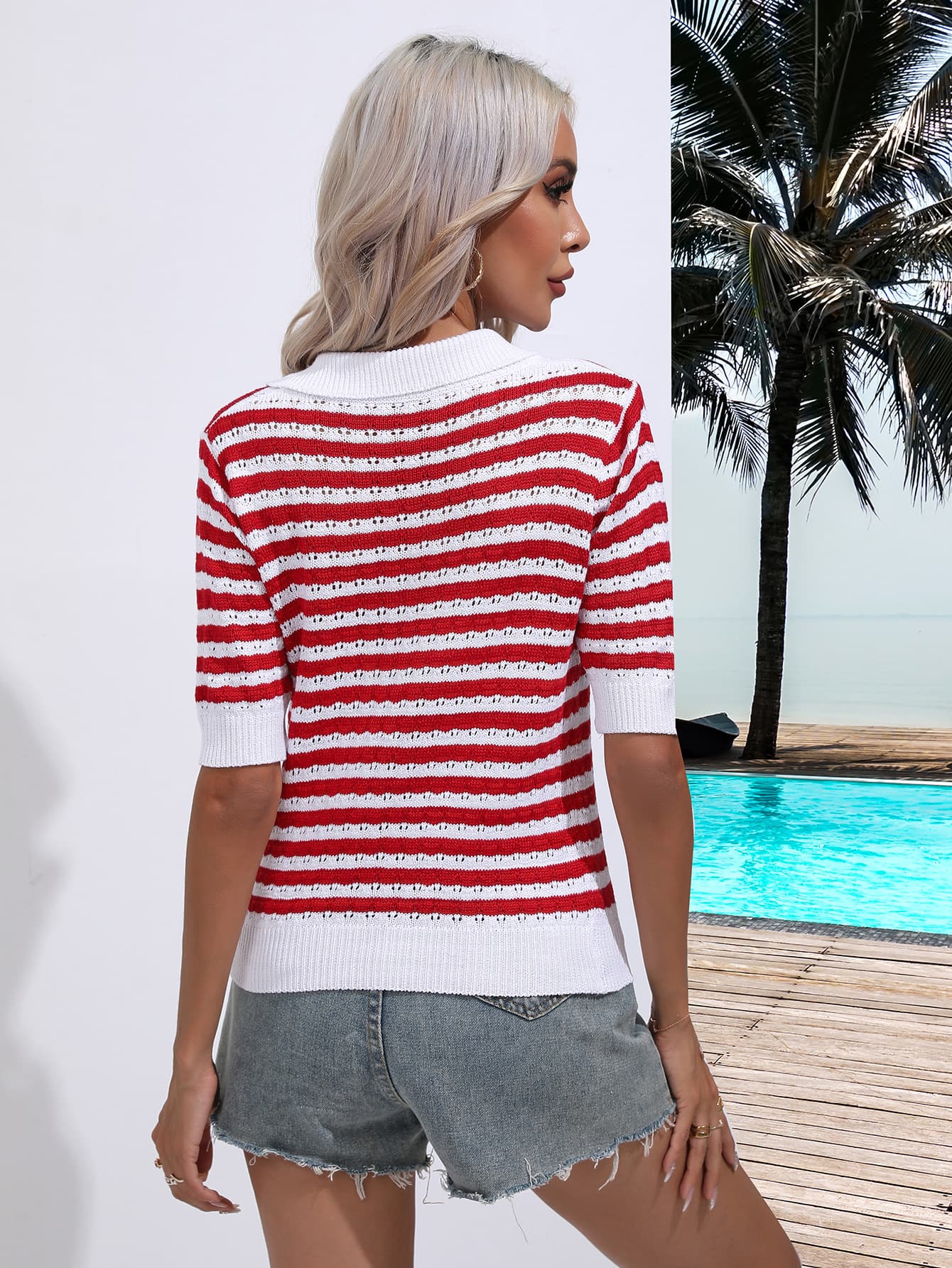 a woman standing next to a pool wearing a red and white striped sweater