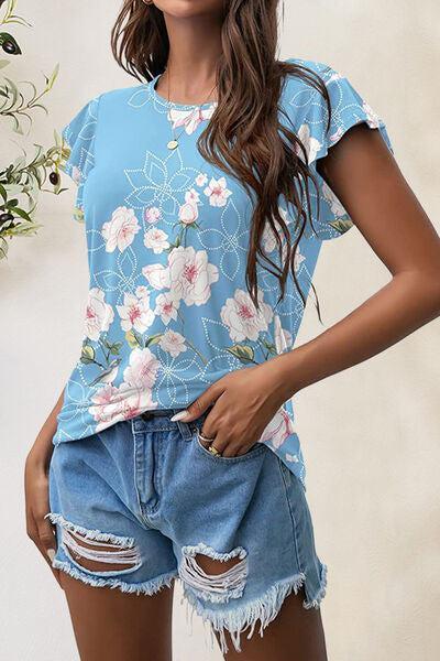 a woman wearing a blue floral shirt and denim shorts