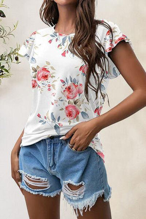 a woman wearing ripped shorts and a floral top
