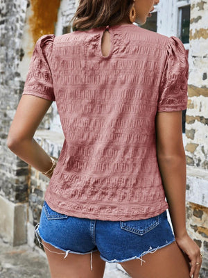 a woman wearing a pink top and denim shorts